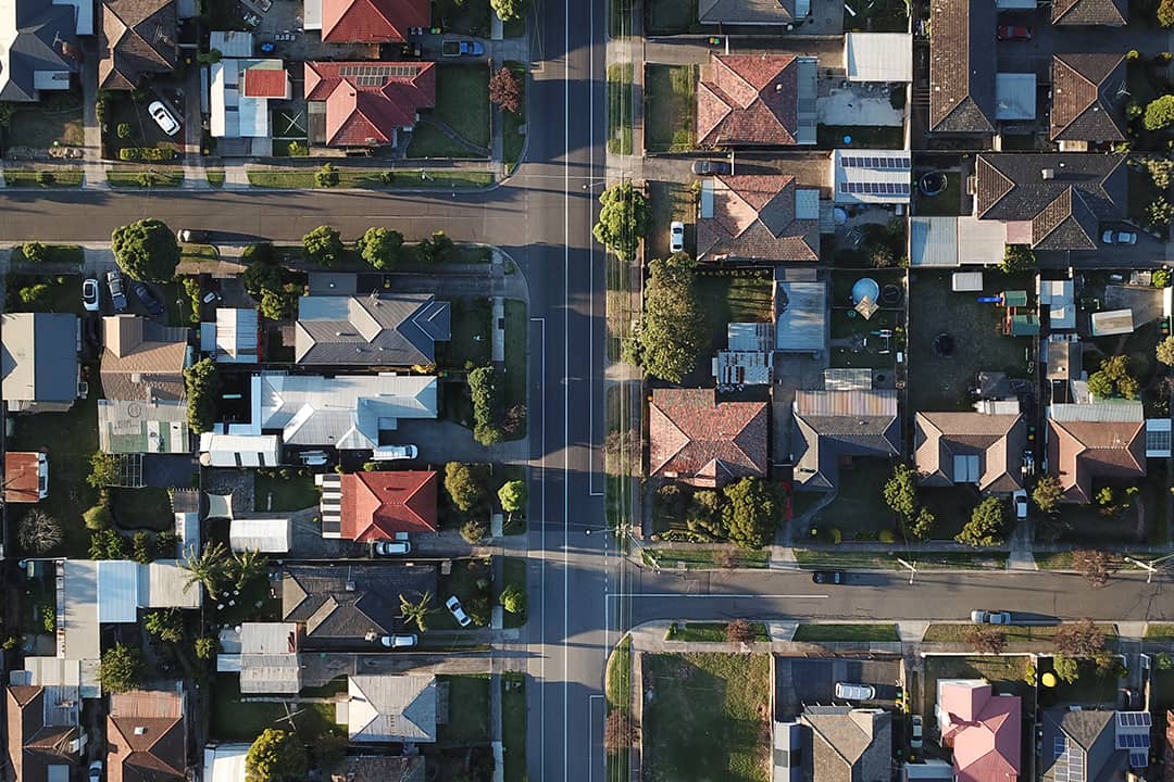 An aerial shot of a downtown street seen through its house rooftops and symmetrical roads during sunset.